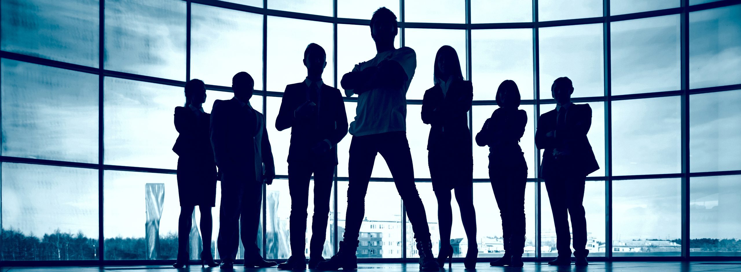 Business team standing against window with leader in front